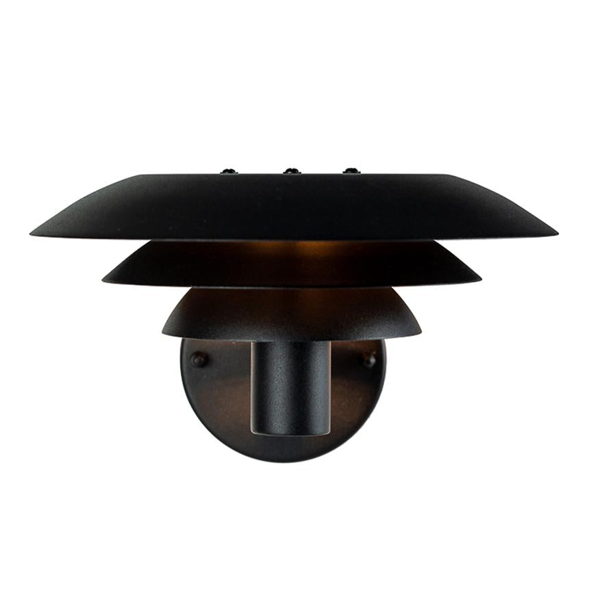Black, layered wall lamp emits warm, diffused light downwards and outwards; mounted on a round wall plate against a neutral white background.