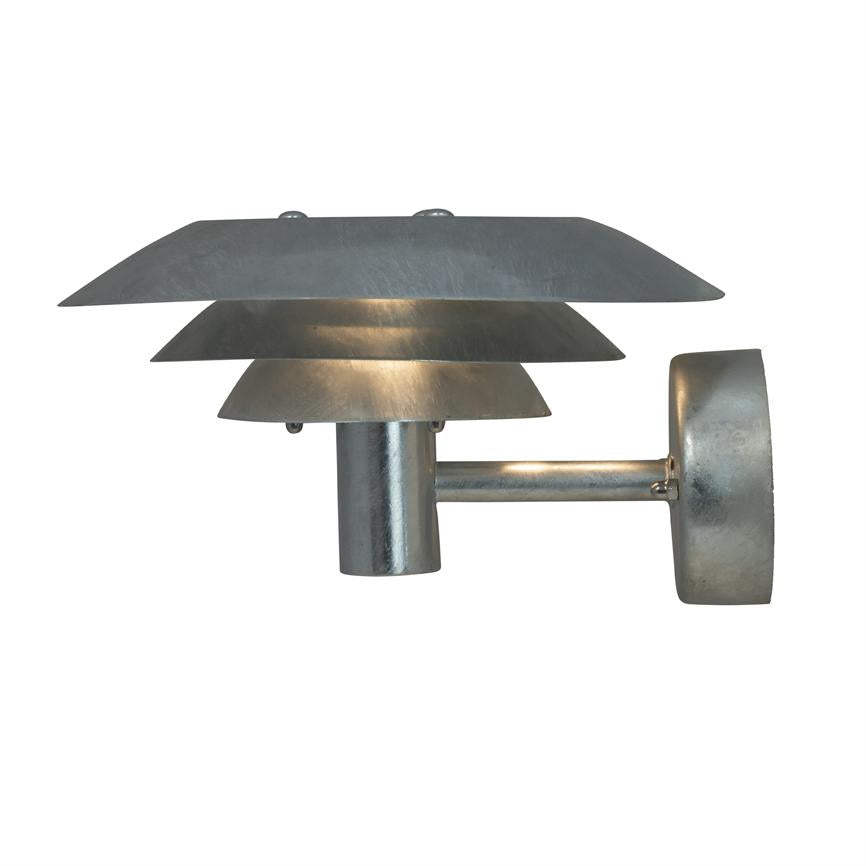 Wall lamp in brushed metal, three layered shades emit warm, subdued light; cylindrical arm connects lamp to round wall bracket, placed against a neutral white background.