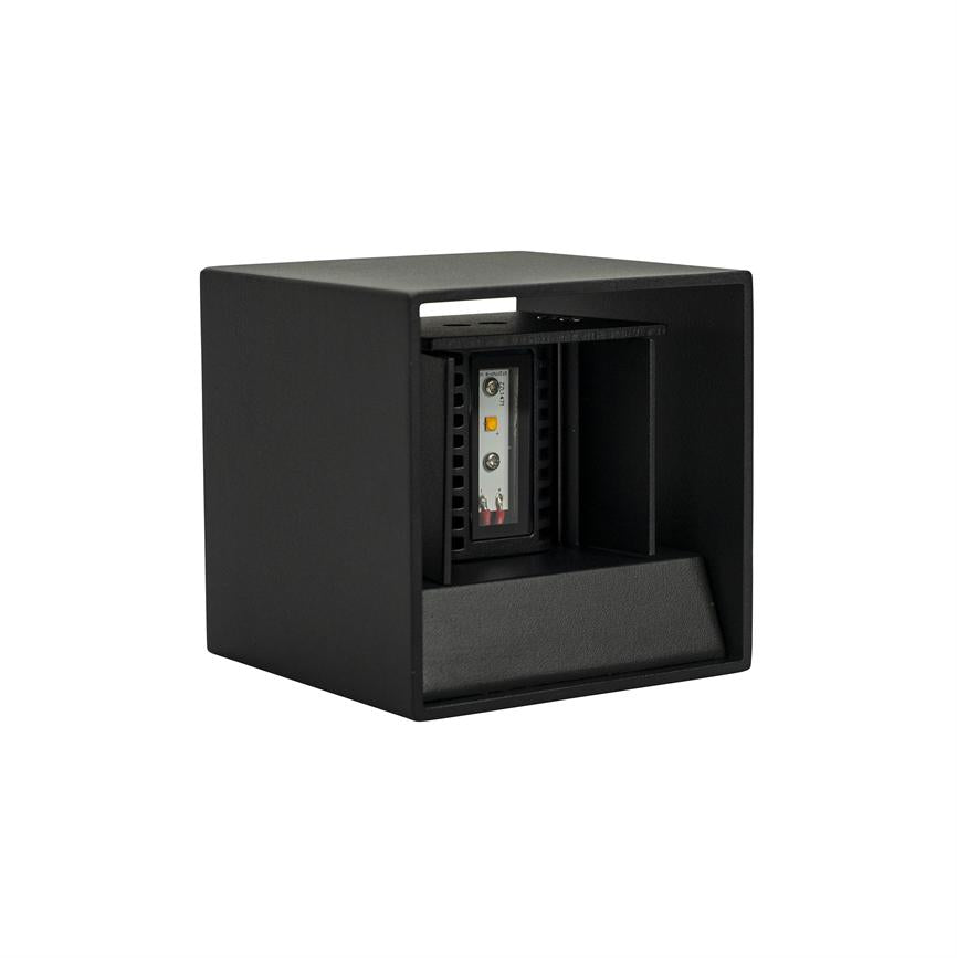 Black cubic fixture shows an internal LED module; the module sits behind an open front panel, directed forward/downward, with a matte finish and spatial notch, shown on a white background.