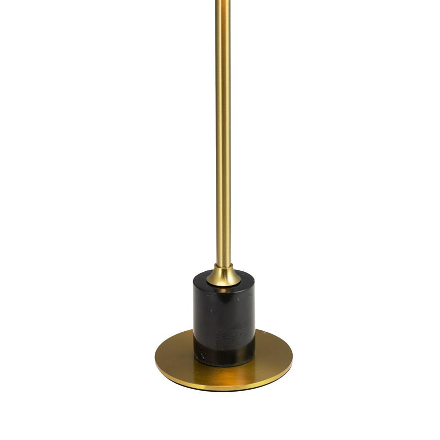 A slender gold-colored rod is mounted in a black marble cylinder, resting on a round gold-plated metal plate; the object stands upright against a uniform white background.