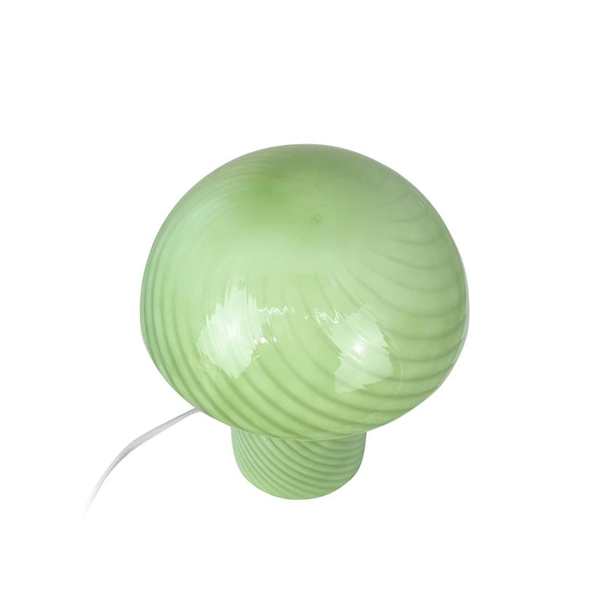 Green, glossy mushroom-shaped table lamp with spiral stripes; it is connected with white wire and stands on a neutral white background.