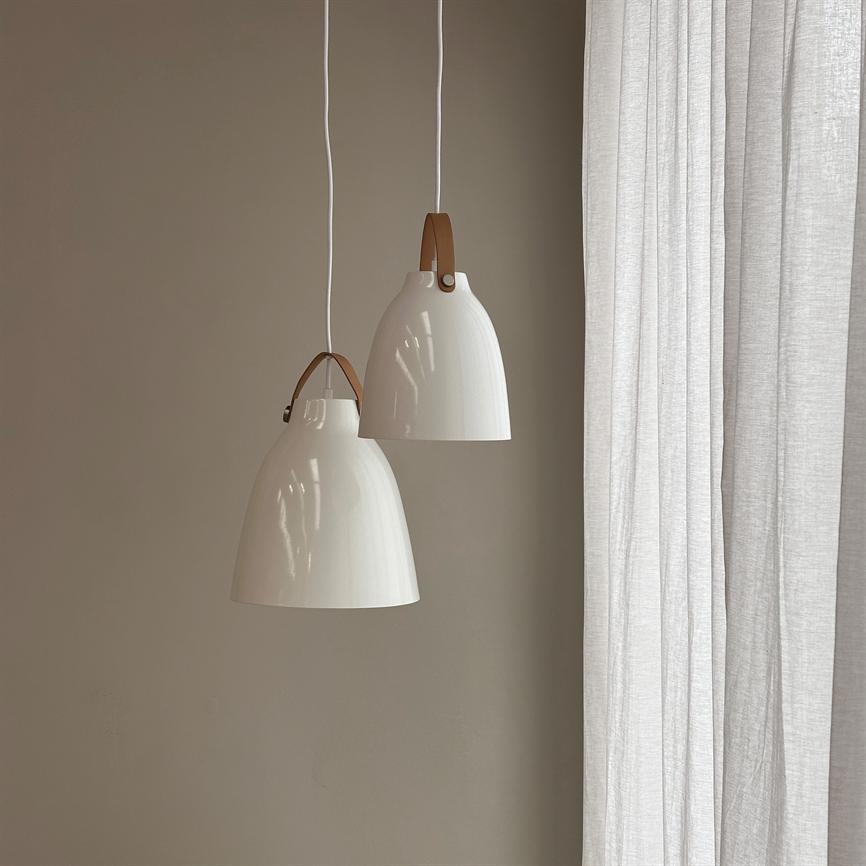 Two white pendant lamps with brown leather straps hang at different heights from the ceiling in front of a warm beige wall, next to slightly transparent light curtains.