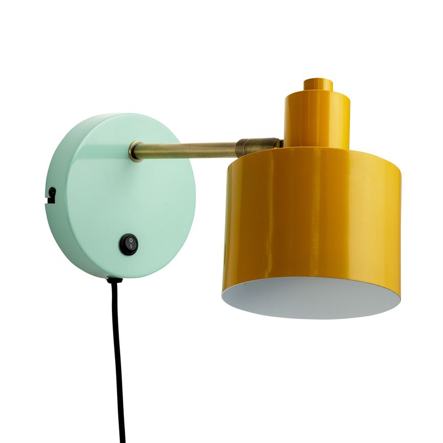 Wall lamp with yellow, cylindrical metal shade points downwards from a brass arm mounted on a mint green, round wall bracket; black cord with switch hangs vertically.