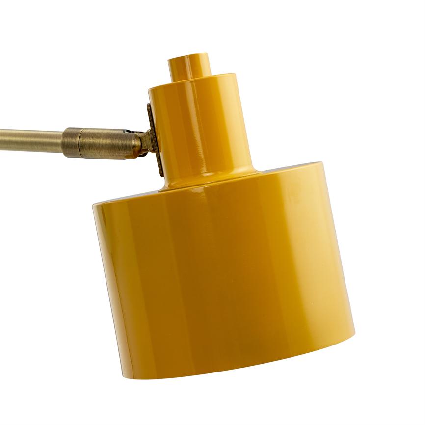 Yellow lamp head mounted on a brass arm, hinged and pointing obliquely downwards; simple, glossy surface against a neutral, white background.