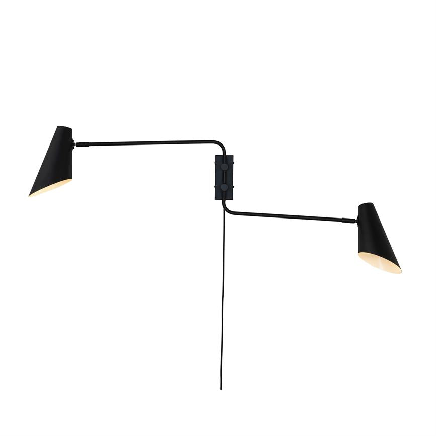 Black wall lamp with two cone-shaped shades that extend on long adjustable arms and cast warm light; mounted on a center plate with a visible hanging wire against a white background.