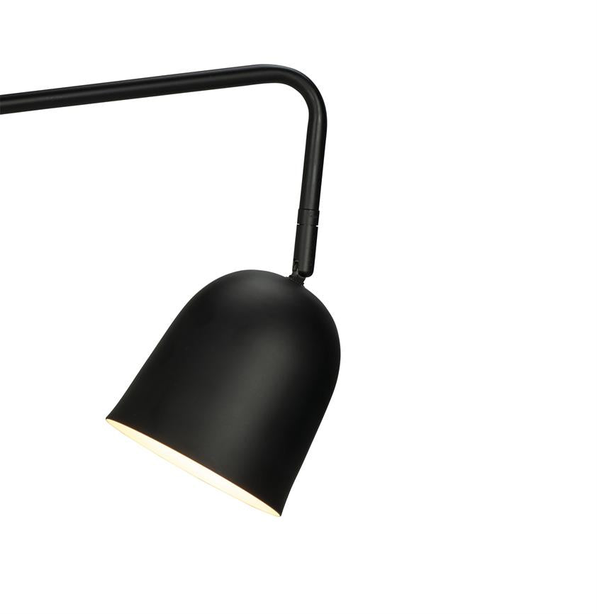 Black metal shade lamp hangs from a curved arm, the shade is tilted downwards and emits warm light; simple, minimalist design against a uniform white background.