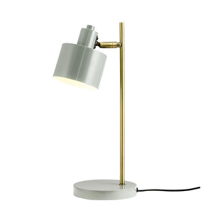 A table lamp with gray cylindrical shade and brass rod; the screen points obliquely downwards and emits soft light, placed on a white background.