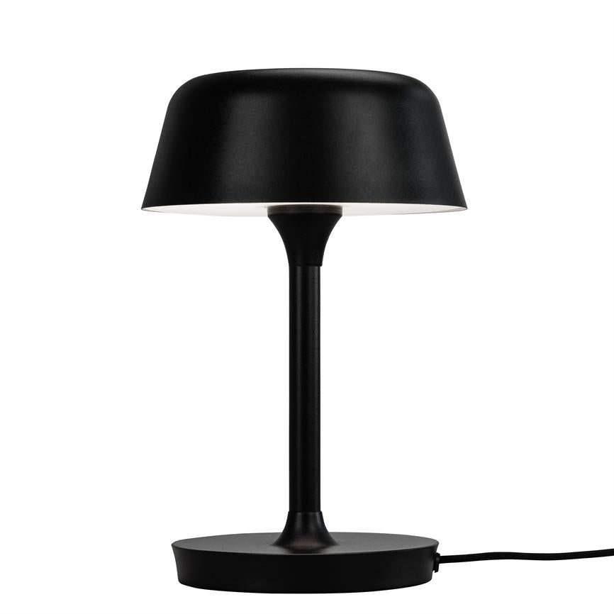Black table lamp stands on a round base, with slender rod and round, downward-facing shade with white interior; placed alone against a uniform white background.