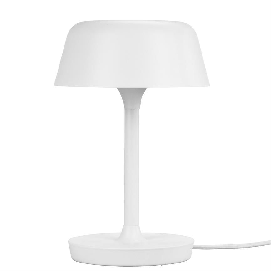 A white table lamp stands upright, with round shade and slim column, placed on a flat round base; wire runs out to the right against a white background.