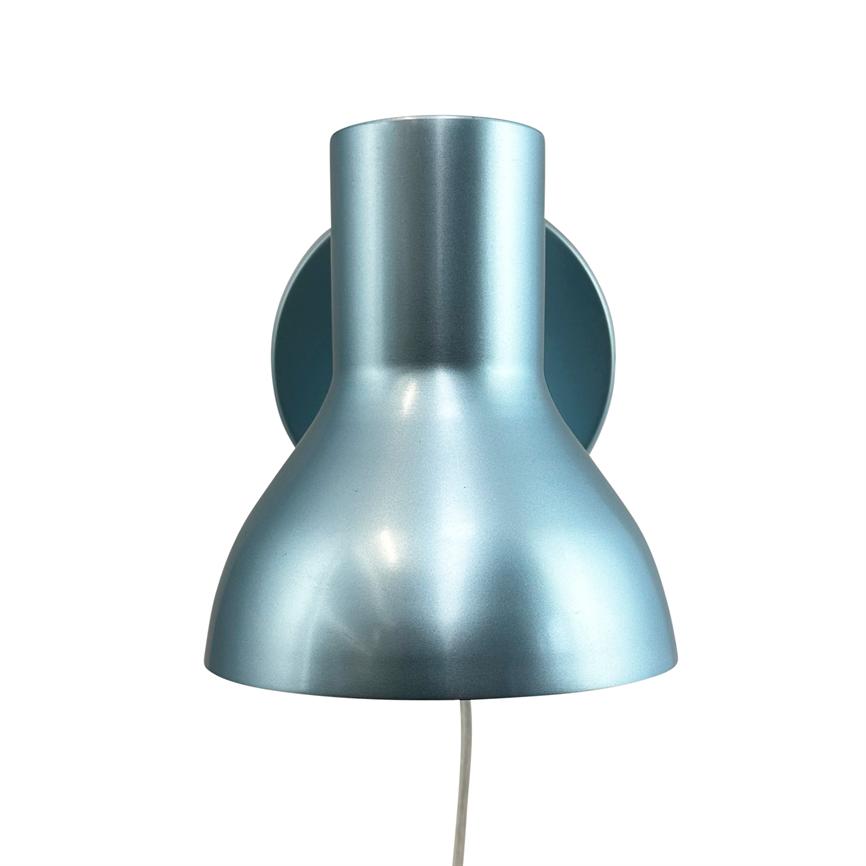 Metallic blue-grey wall lamp mounted on a round wall bracket; the screen faces down, a thin white wire hangs down, set against a uniform white background.