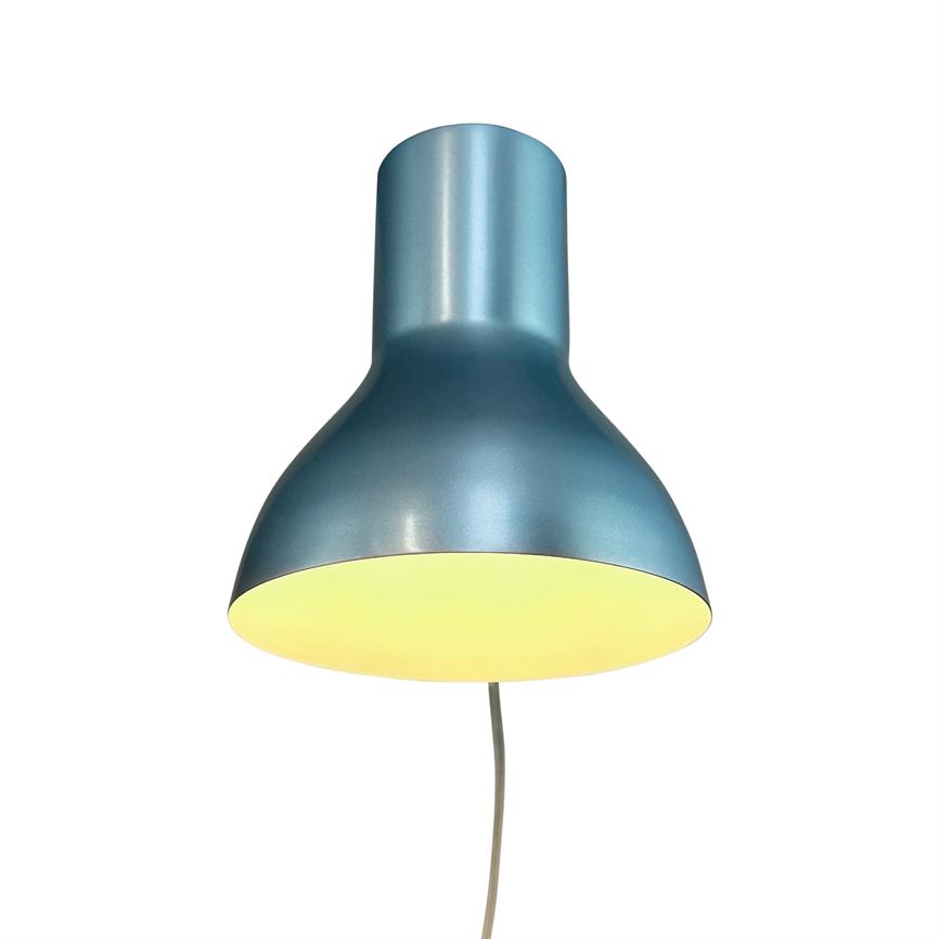 A metallic blue pendant light glows warmly from within; it hangs by a slender cord against a neutral white background, depicted from the front with the screen's yellow cone of light facing downwards.