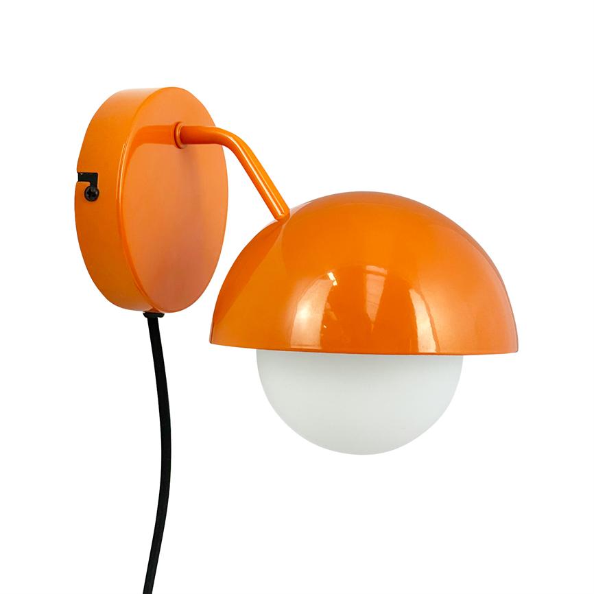 A wall-mounted orange lamp with a hemispherical shade covers a white glass dome; a short arm connects to round wall plate, black wire hangs down.