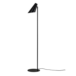 Black floor lamp stands upright, shade points obliquely downwards; slim metal rod on round foot with visible wire, placed against white background.