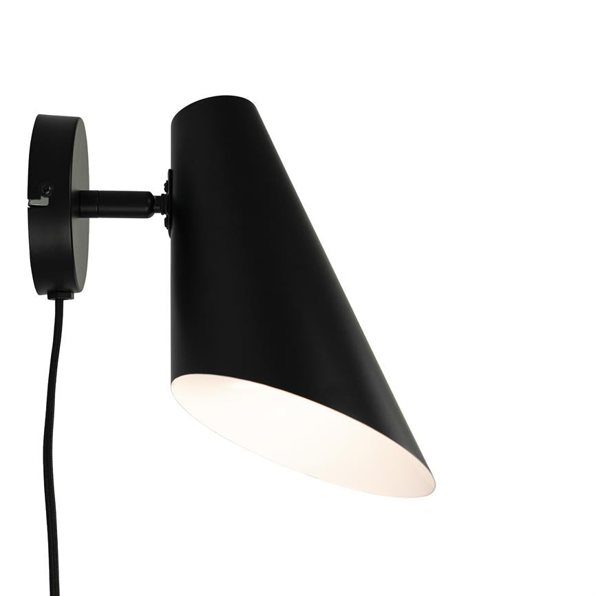 Black, cone-shaped wall lamp mounted on a round wall bracket; the lampshade points downwards, white interior and black fabric cord hangs freely in a minimalist white background environment.