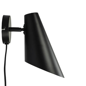 Black matte metal wall lamp with pointed, slanted lampshade; mounted on round wall bracket, cable hanging down, screen angled downwards against white background.