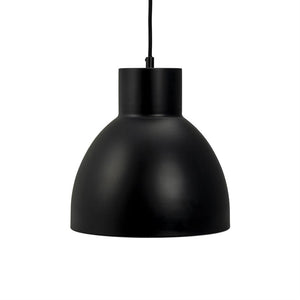 A black metal pendant lamp hangs from a thin black cord; its matte, round dome shields the light downwards against a clean, white background in a minimalist expression.