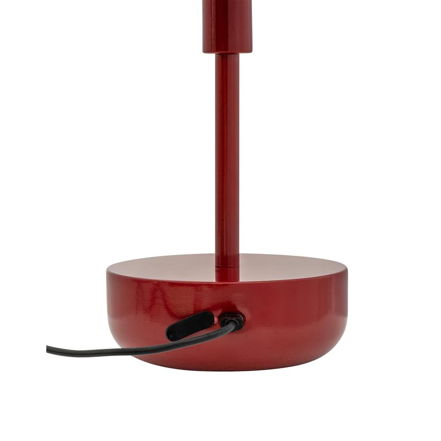 Red lamp base with vertical rod; it has a black power cord inserted into the side and stands centrally on a uniform white studio background.