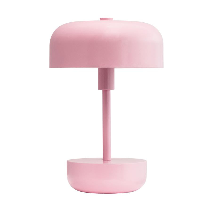 Table lamp stands vertically; has cylindrical stem, rounded shade and bowl-shaped base in solid pink; placed against a neutral white background.