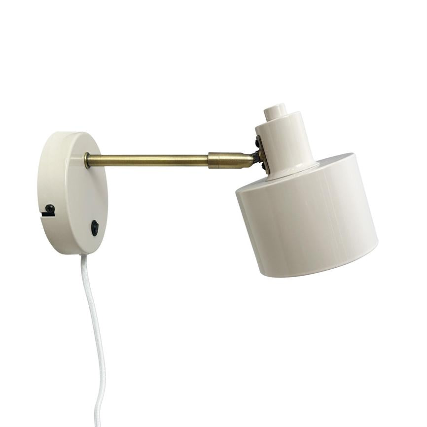 Wall lamp with cylindrical white shade, tilts forward on an adjustable brass arm; mounted on round white wall plate with visible white fabric cord, against a uniform white background.