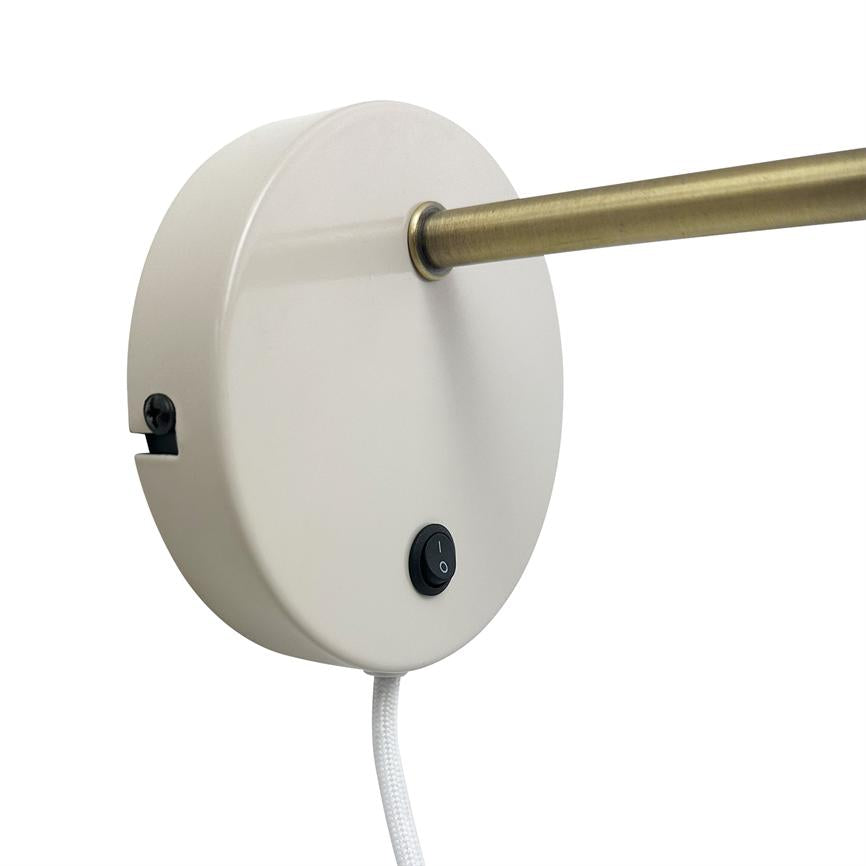 Round white wall base (lamp fitting) holds a thin brass rod, has a black on/off button and a white braided cord, mounted against a neutral light background.