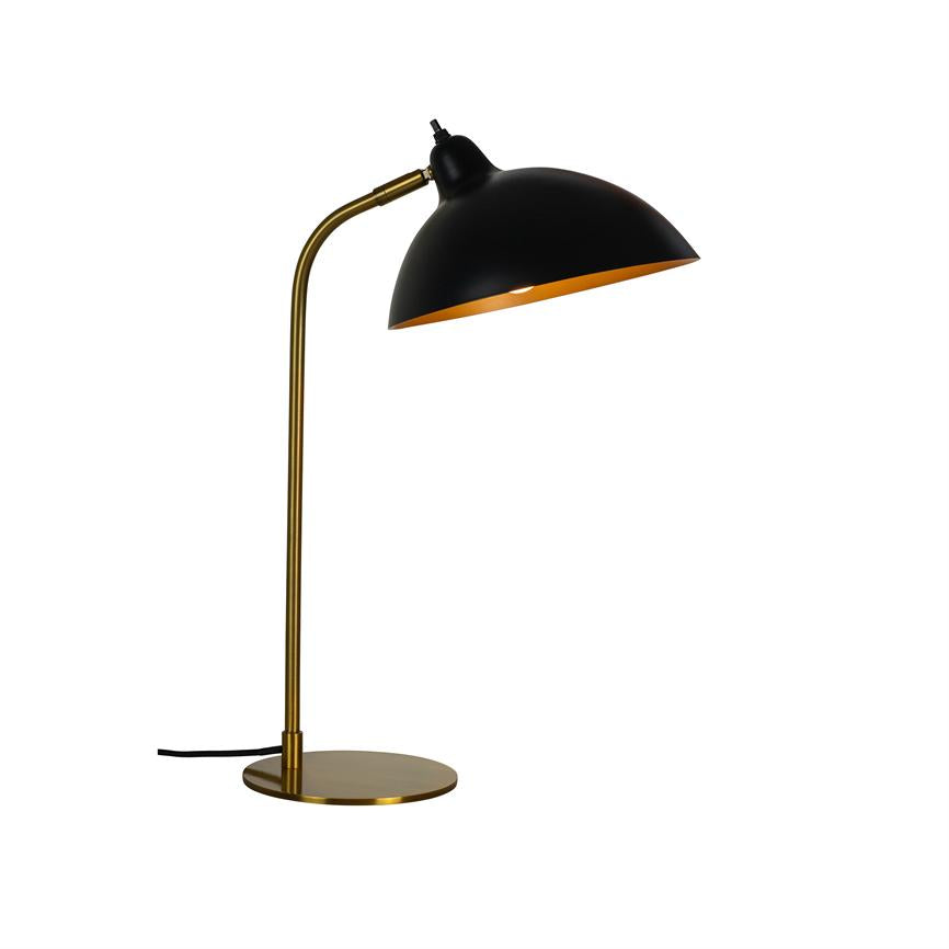 A desk lamp with a black dome shade and golden interior, tilted downwards and casts light; slim golden stand and flat round base on white, neutral background.