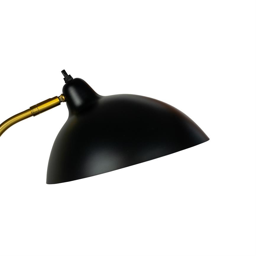 Black hemispherical lampshade points downwards and right, mounted on a curved brass arm; simple, matte surface against a white background.