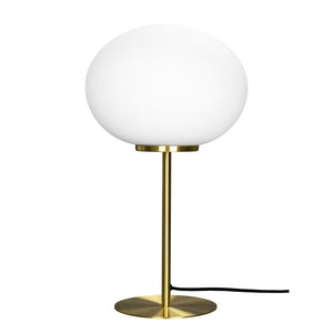 En bordlampe med hvid rund globus står på en slank messingstang og cirkulær messingfod; en sort ledning ligger ved siden af, mod en ensartet hvid baggrund.
