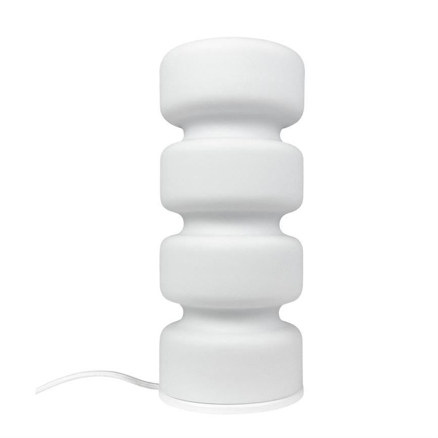 White table lamp stands on white background; it consists of four rounded, stacked sections and a visible white wire, minimalistic and modern design.