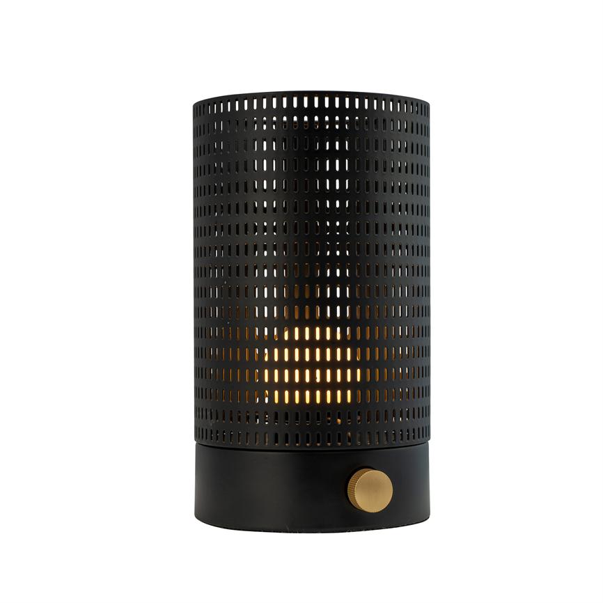 Cylindrical black metal table lamp with perforated shade, emits warm golden light through small rectangular holes; black round base with gold dial, neutral white background.