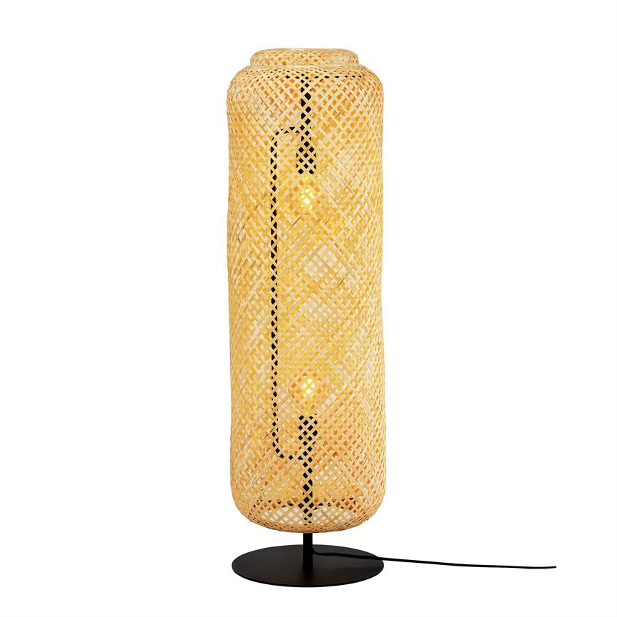 Tall cylindrical wicker rattan lamp emits a warm, golden glow; two visible incandescent bulbs in black metal base with cord, placed in front of a white background.