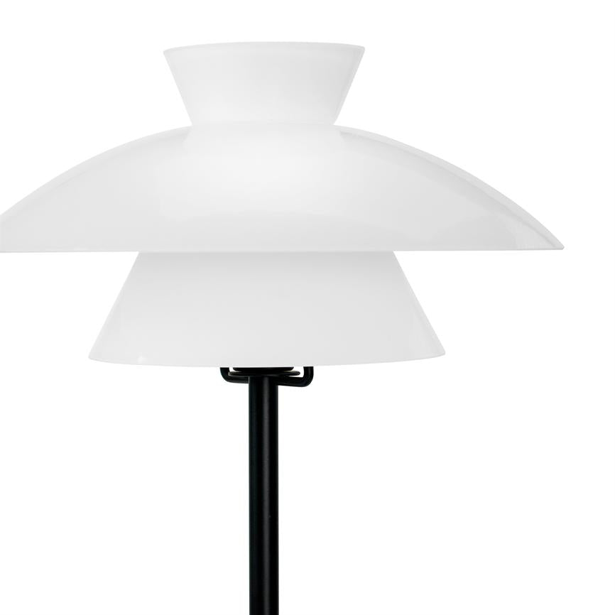 Lamp with three white, layered shades stands on a black pole; it shows a minimalist design and is isolated against a neutral white background.