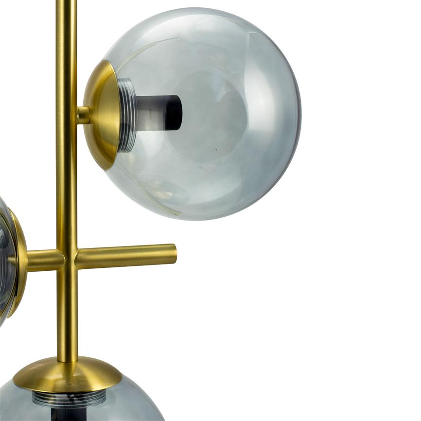 Smoke colored glass globe mounted on a vertical brass rod; the glass bowl sits in a gold-toned socket and reflects light, in front of a neutral white background.