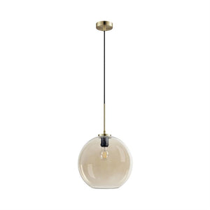 A round glass pendant hangs in black cord and brass disc, with a transparent, slightly golden glass shade and a visible filament bulb inside, against a neutral white background.