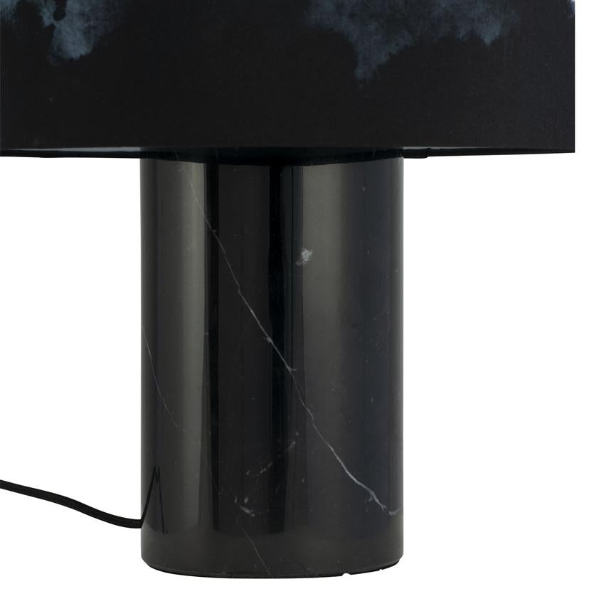 Black cylindrical marble base under a dark rectangular lampshade; stands still on a white background with visible white veins in the marble and a black cord to the left.