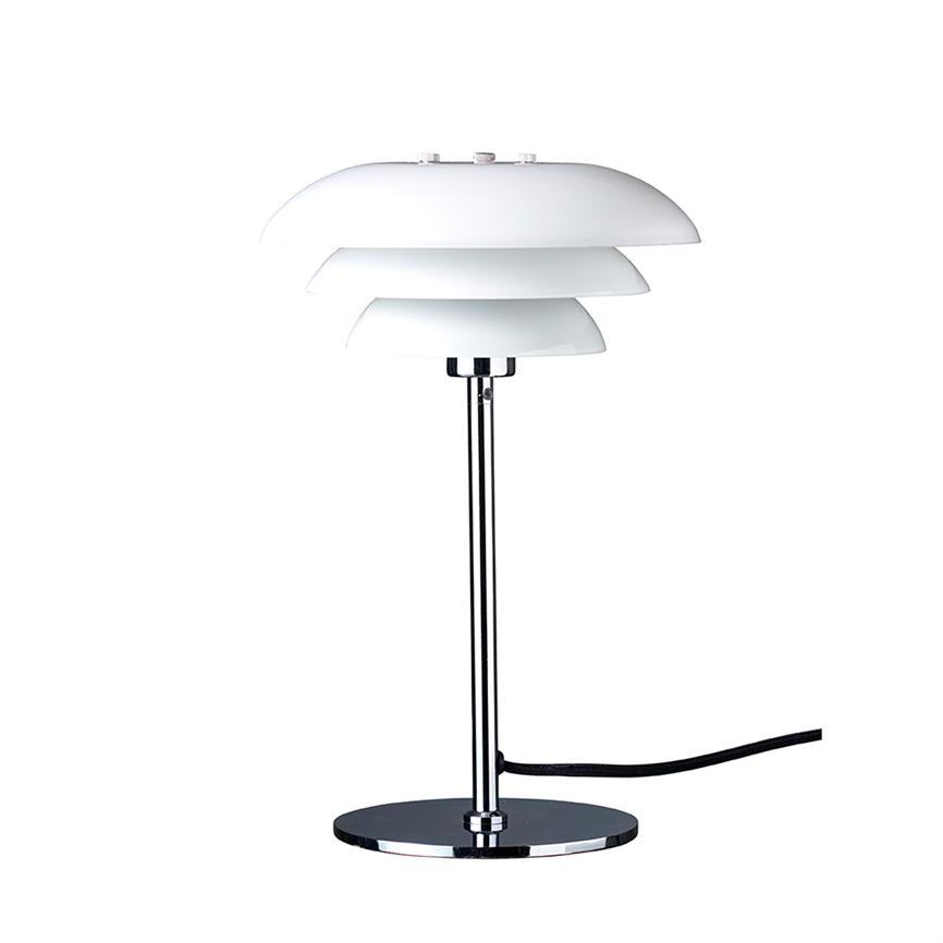 Table lamp stands on a round chrome base, supported by a slim chrome rod; three tiered white lampshades at top; black wire leads out to the right on white background.
