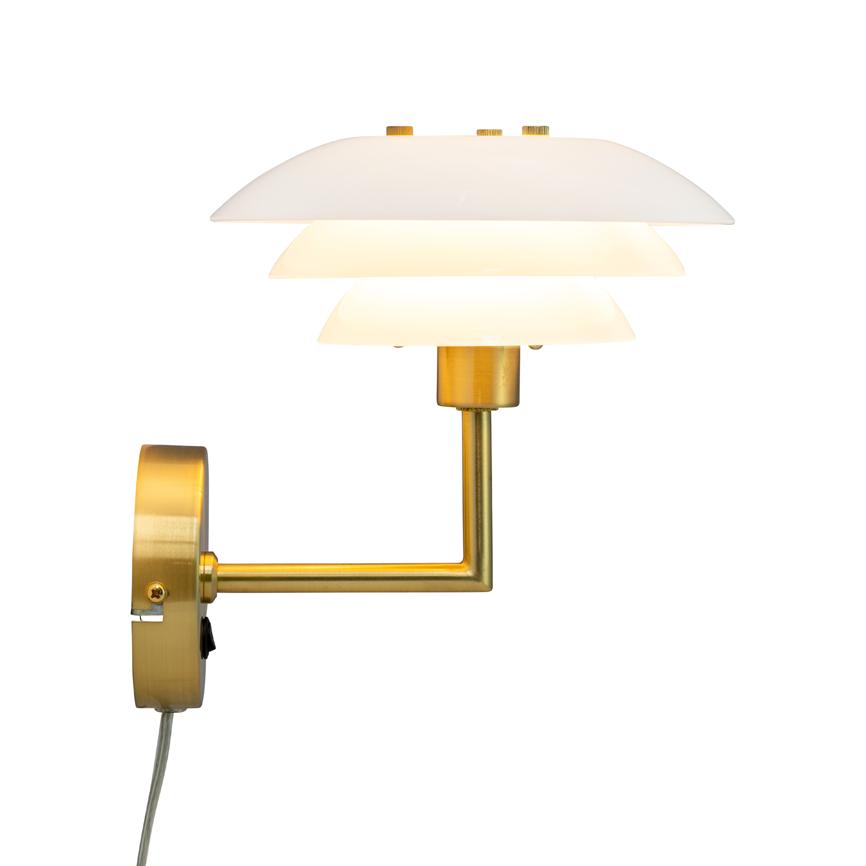 Wall lamp with three white shades that emit warm, diffused light; mounted on a gold-coloured arm and wall bracket, appears in a minimalist, white room.
