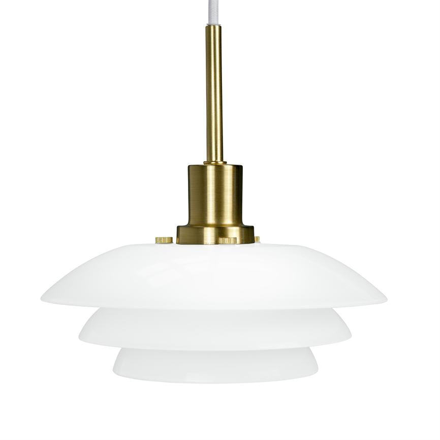 A ceiling pendant hangs from a white fabric cord; brass fittings connect three layered, white opal glass shades that diffuse soft light. The background is neutral white.