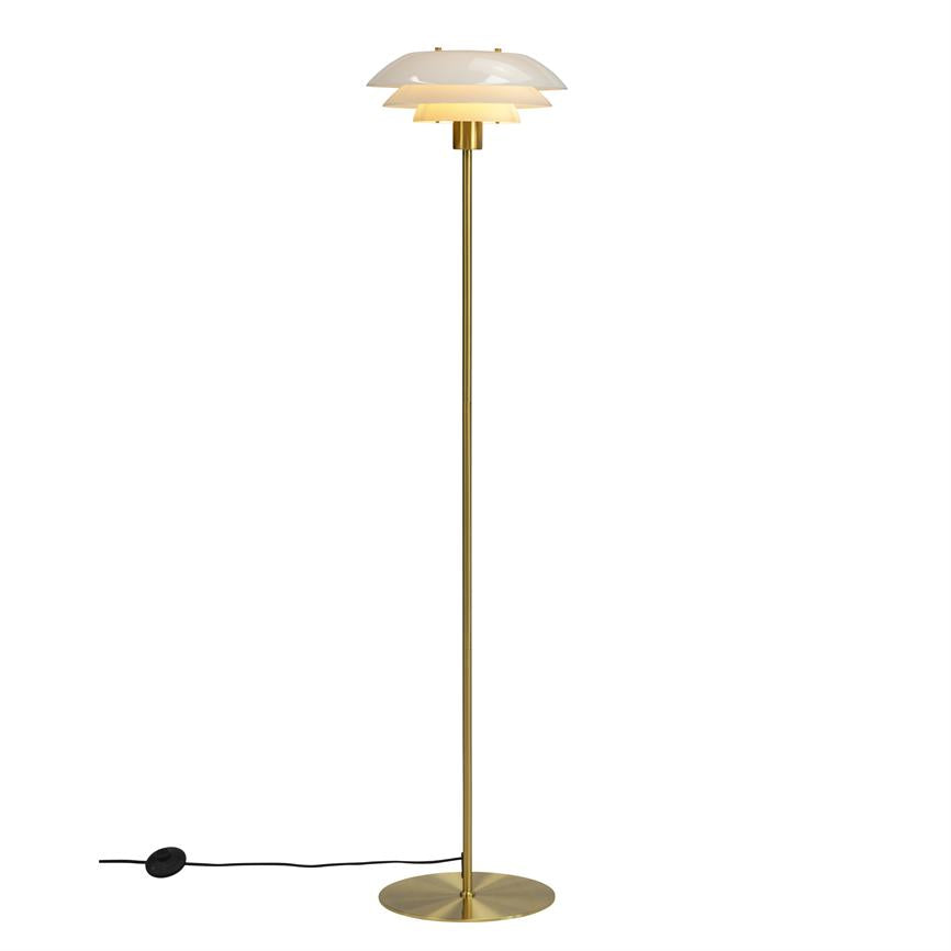 Floor lamp with three white shades emits warm light; stands on a slender brass rod with a round foot and black cord against a white, neutral background.