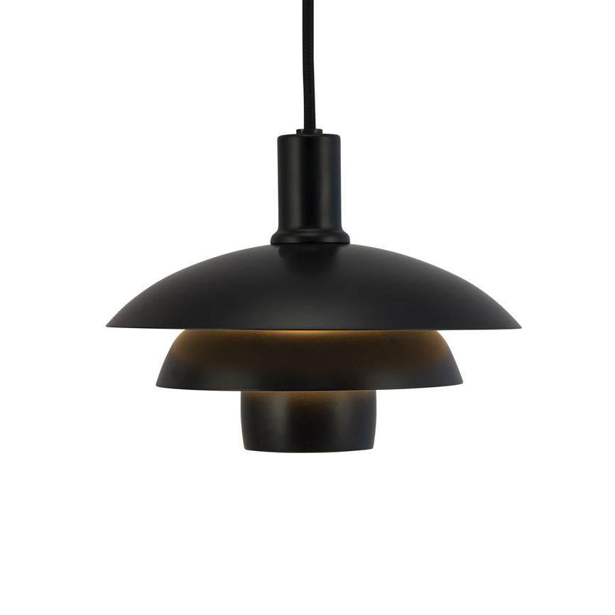 A black, three-layer pendant lamp hangs from a black cord, emitting warm, downward-facing lighting from interior shades against a neutral white background.