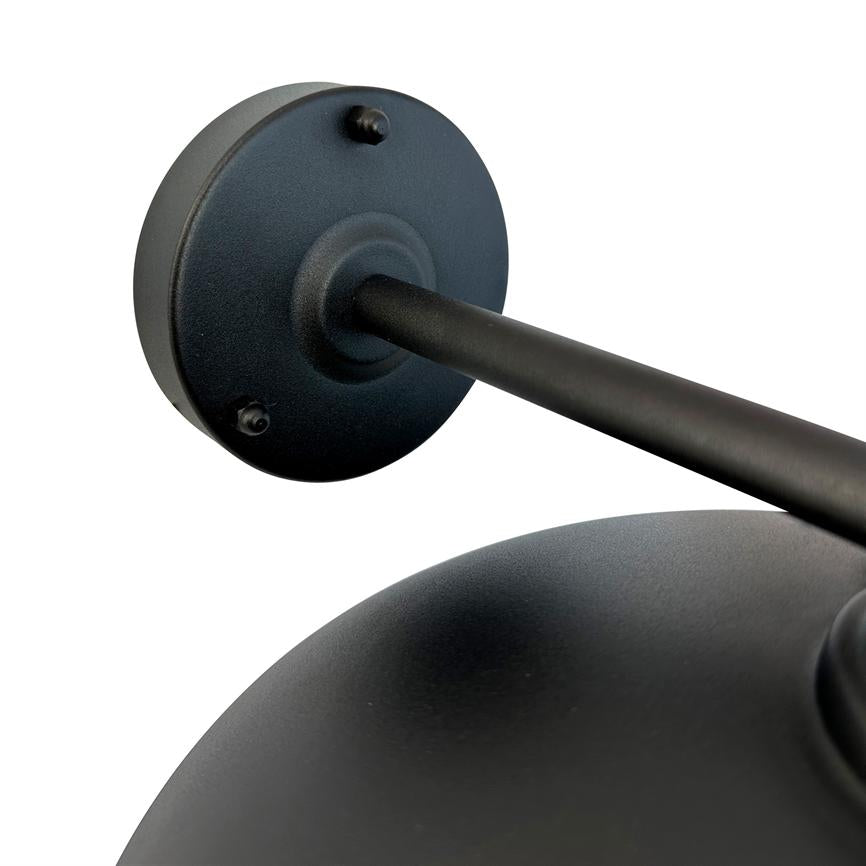 Matt black metal wall lamp: round wall bracket and arm extending diagonally towards a domed shade; close detail on a white, neutral background.