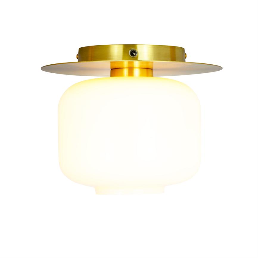 Ceiling lamp with round, milky-white glass shade shines soft, warm-toned light; brass fittings fixed to the ceiling against a neutral white background.