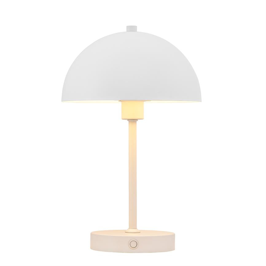 Table lamp with semi-domed shade, emits soft warm light, mounted on slim rod and round base, stands centrally against uniform white background.
