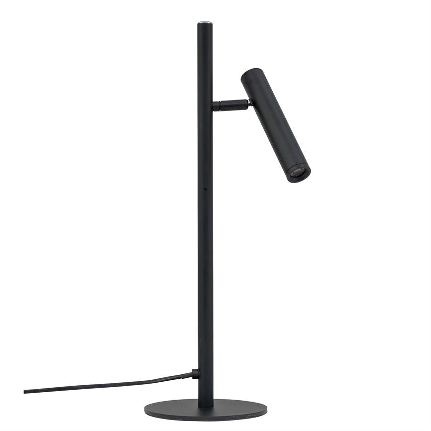 A slim black table lamp with a cylindrical, adjustable lamp head that points obliquely downwards; mounted on a vertical pole and round base, with visible power cable on a white background.