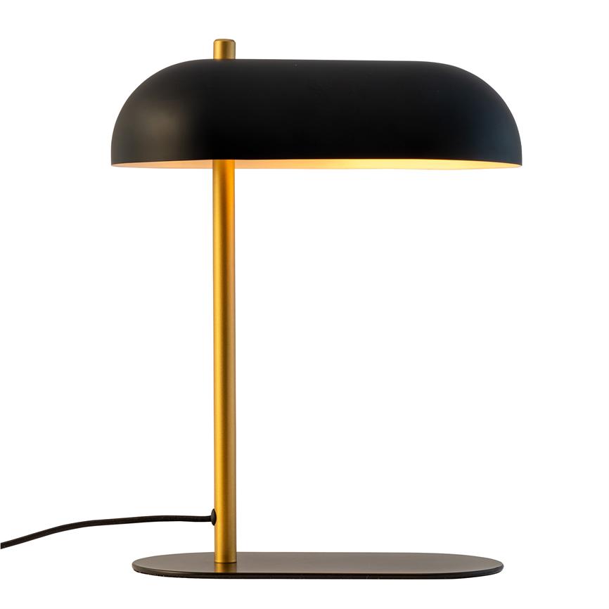 Table lamp with black dome shade and gold colored rod; emits warm light downwards; stands on flat, oval black foot with cable to left on white background.