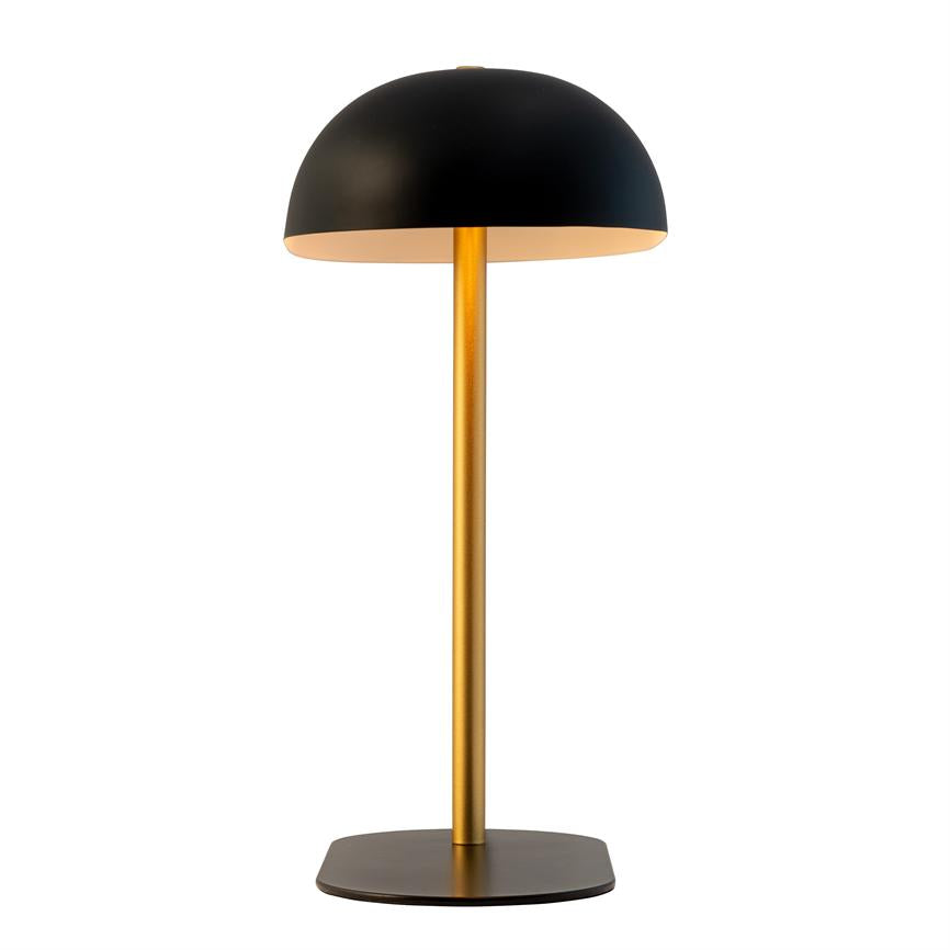 A table lamp with black dome, golden rod and square black base; it emits warm, downward-facing light and stands alone on a neutral, white background.