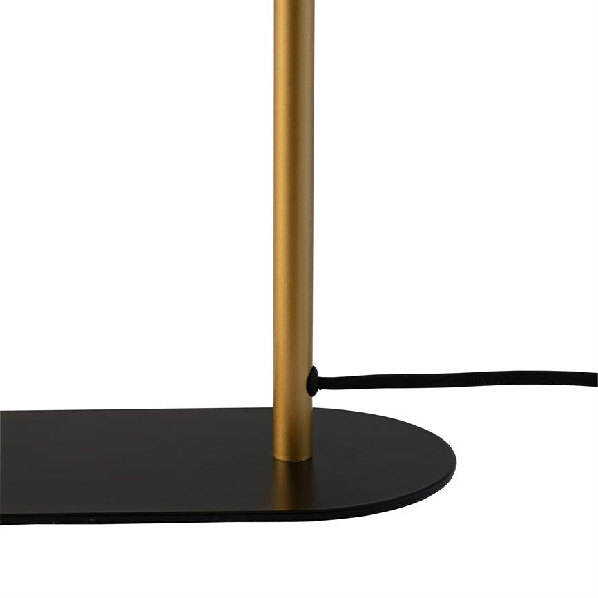 Golden lamp rod stands vertically in a flat black oval base, with a black power cord passed through a hole and lying against a white background.