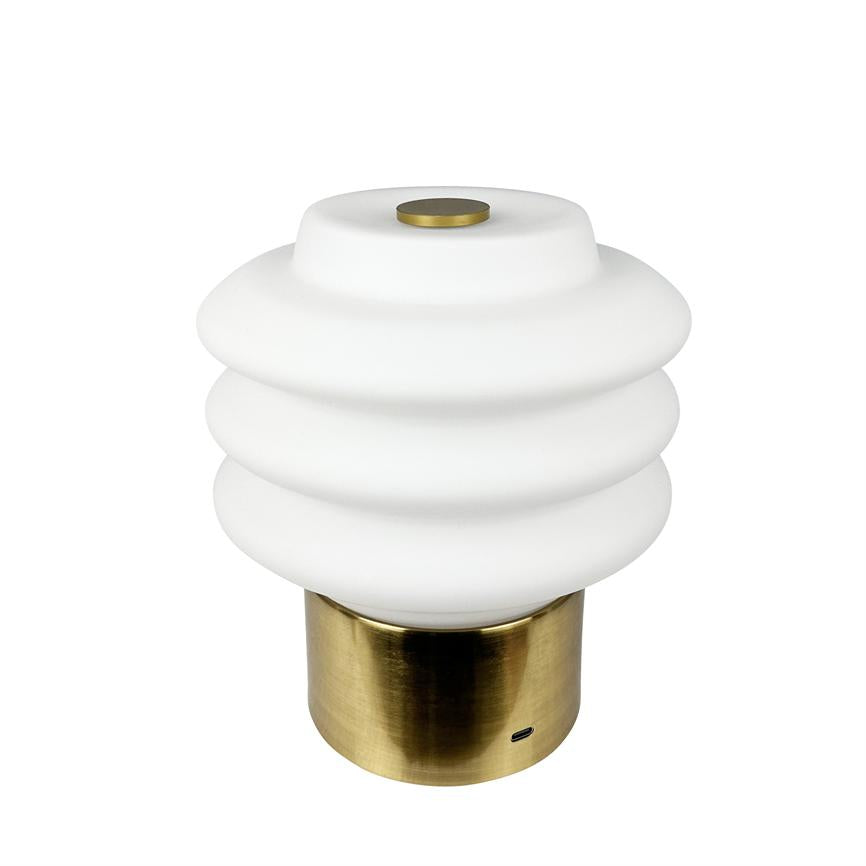 Table lamp with white, wavy shade in three rings stands on a cylindrical brass base on a white background; a small USB-C port is visible in the foot.