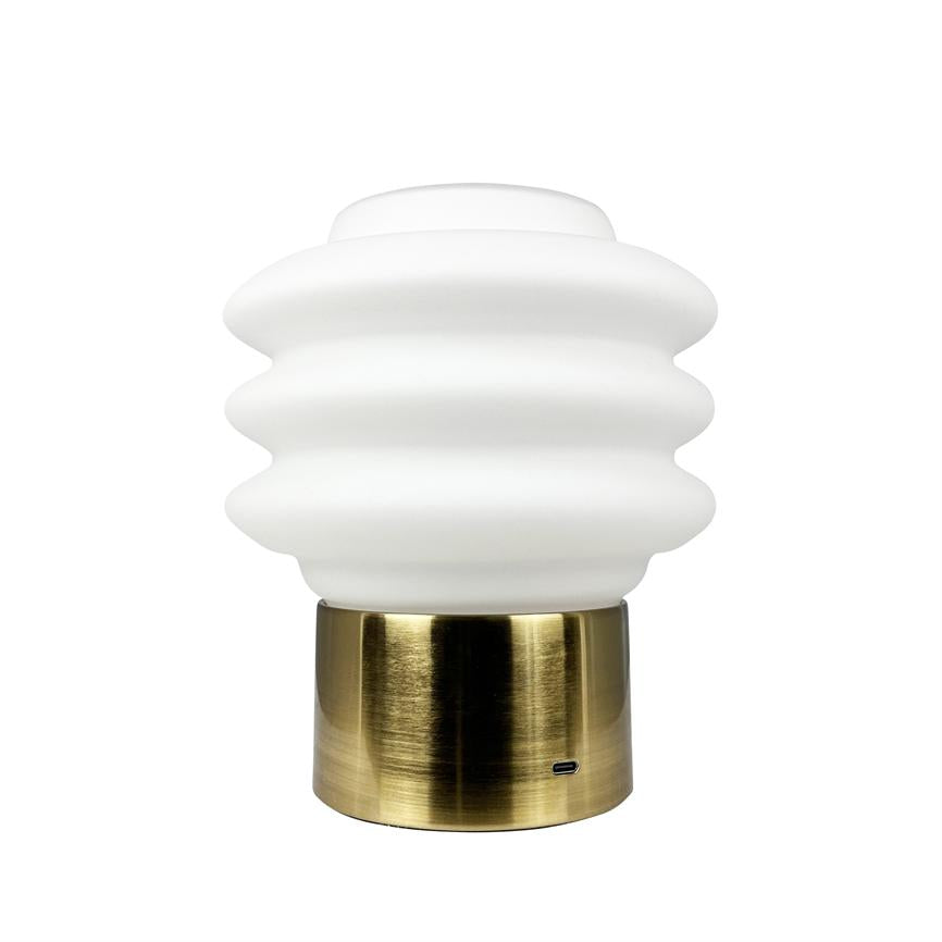 Table lamp: wavy, white opal glass dome sits on a brass-colored cylindrical base; the lamp is turned off and placed against a neutral white background; visible USB-C port at the bottom.