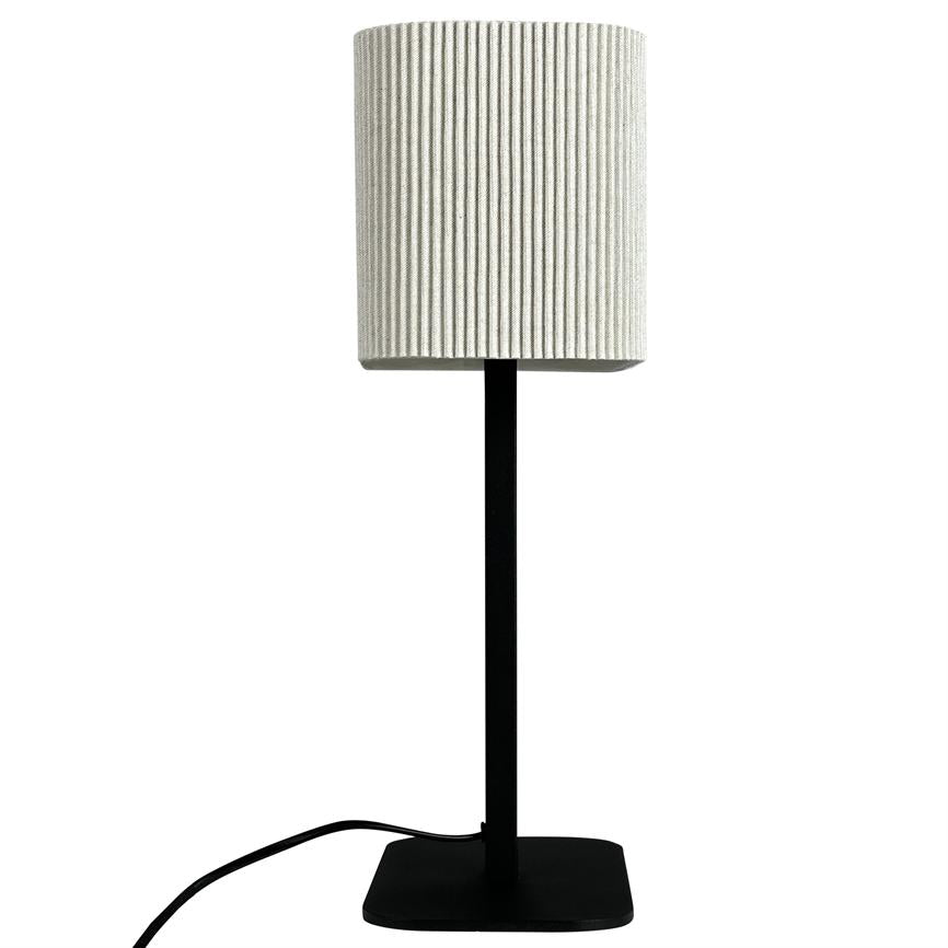 Lamp stands vertically on a black, square foot with thin rod; a white, grooved cylindrical screen sits at the top, and a black wire runs along the white background.