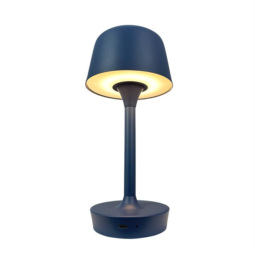A blue table lamp emits warm, downward light from a round shade; it stands on a cylindrical stand with USB-C port in a white isolated studio/product photo.